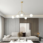 Gold and white Clérachic chandelier in a grey living room, with a large pale print and pampas grass on a coffee table.
