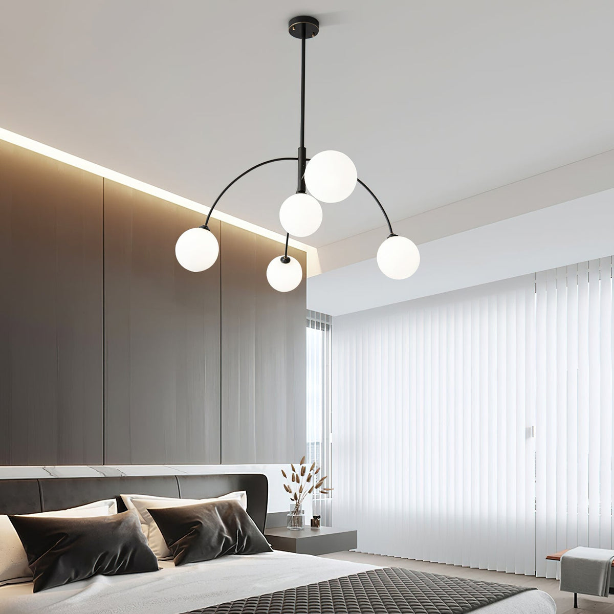 Black and white Clérachic chandelier above a dark-toned bed with black and cream cushions, a recessed ceiling light strip above.