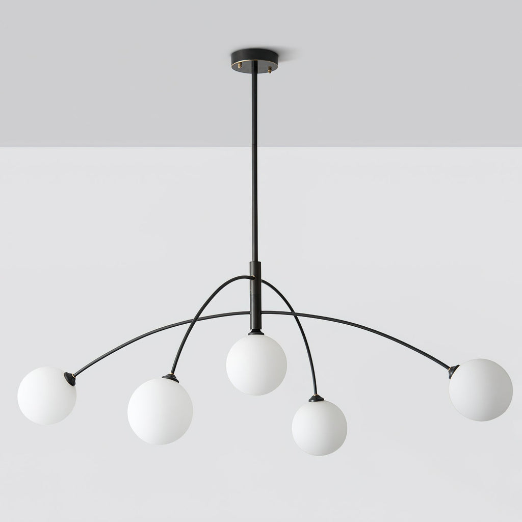 Black and white Clérachic chandelier on a pale grey ceiling and wall, seen straight on with its rod and ceiling plate.