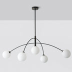 Black and white Clérachic chandelier on a pale grey ceiling and wall, seen straight on with its rod and ceiling plate.