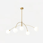 Gold and white Clérachic chandelier with a brass ceiling cap and rod, five lit globes glowing on a soft white backdrop.
