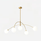 Gold and white Clérachic chandelier lit against a soft grey backdrop, its globes glowing on thin brass arms.