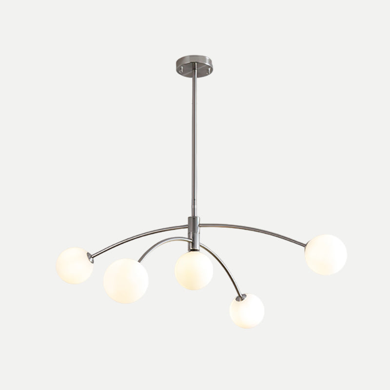 Chrome Clérachic chandelier with lit globes, a round ceiling plate and a slim rod on a pale background.