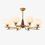 This Clérachic chandelier has frosted white globes on brass arms around a walnut cone and brass rod, on a plain white backdrop.