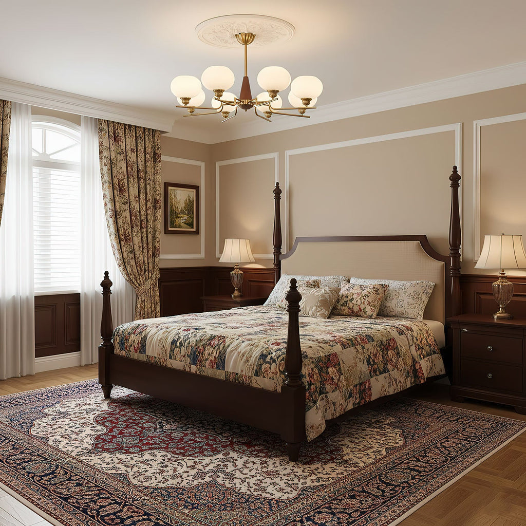 A Clérachic chandelier hangs above a dark four-poster bed with floral bedding, in a bedroom with cream panelled walls and a patterned rug.