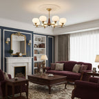 In a room with navy panelling, a white fireplace and a burgundy sofa, a Clérachic chandelier hangs from a plaster ceiling rose.