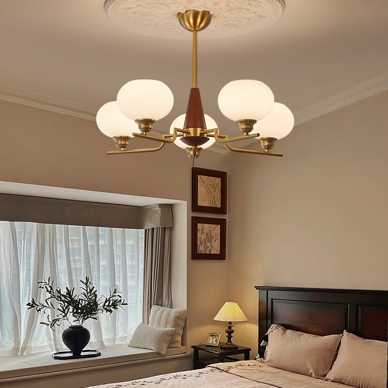This Clérachic chandelier lights a bedroom with a dark wood bed, a bay window seat and a small table lamp on the bedside table.