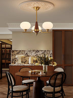 Over a dining table with black cane chairs, a three-light Clérachic chandelier hangs from a plaster ceiling rose.