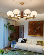 This Clérachic chandelier hangs in a living room with a big abstract painting, a cream bouclé sofa and a green rug.