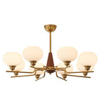 This Clérachic chandelier has eight globes on brass arms around a walnut cone, shown lit on a white backdrop.