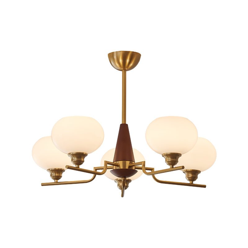 The brass canopy and rod of this Clérachic chandelier lead down to a walnut cone and three lit white globes, on white.