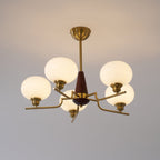 The warm glow of five milky globes lights up this Clérachic chandelier, shown against a soft grey wall.