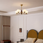 A Clérachic chandelier hangs from a coved ceiling in a bedroom with white wall panels and a mustard arched headboard.