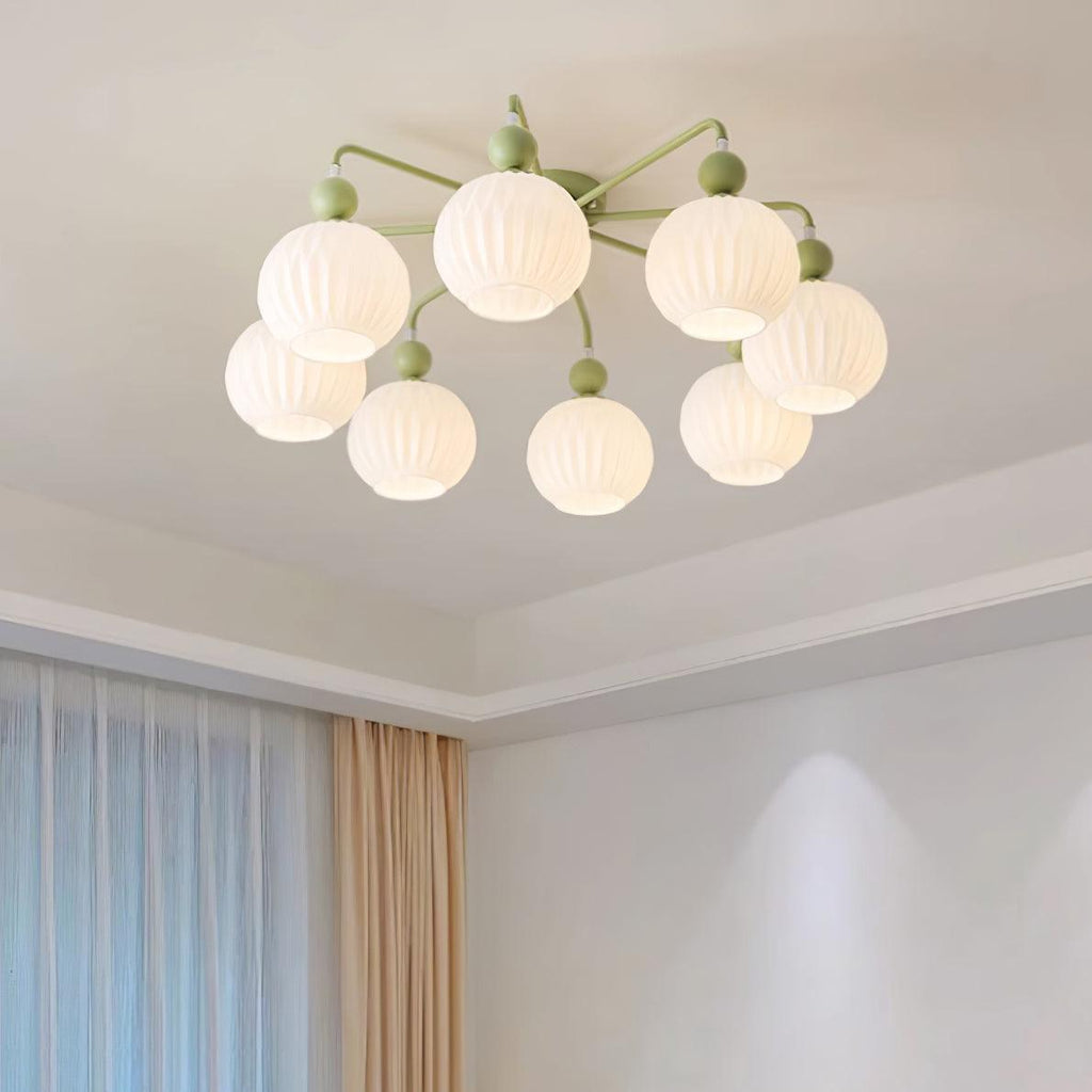 Lit eight-globe Clérachic ceiling light in green, seen from below on a ceiling with a stepped edge and sheer curtains beside it.