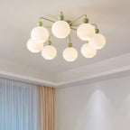 Lit eight-globe Clérachic ceiling light in green, seen from below on a ceiling with a stepped edge and sheer curtains beside it.