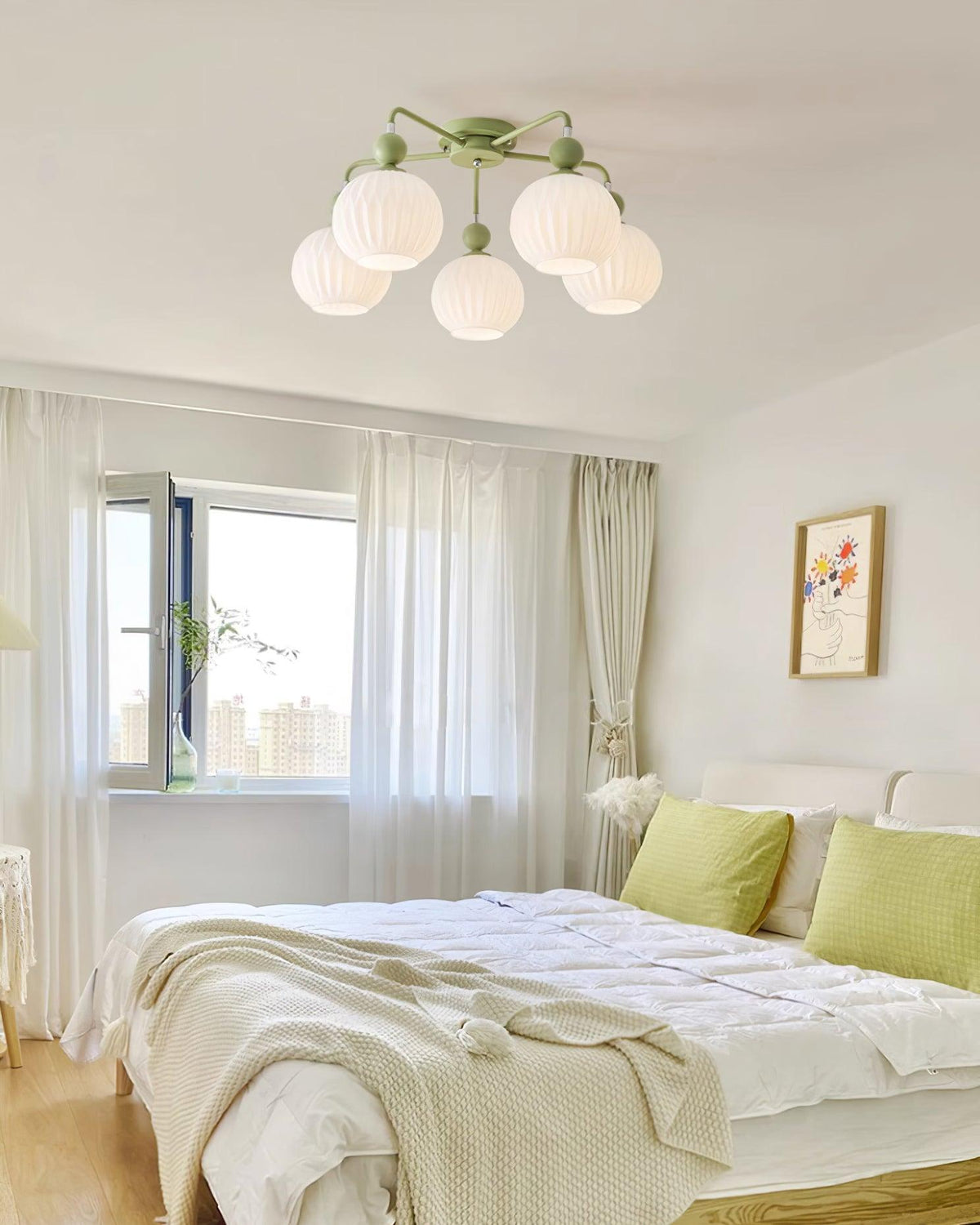 A five-globe Clérachic ceiling light in green above a bedroom with white bedding, lime cushions and a sheer-curtained window.