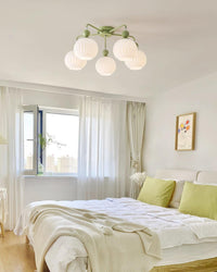 Small framed view of a green Clérachic ceiling light above a bright bedroom with lime-green cushions and a window.
