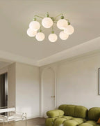 The green Clérachic flush-mount light above a living room with an olive-green bouclé sofa and an arched doorway.