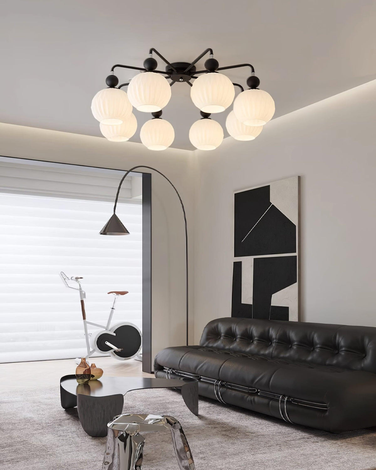 Black Clérachic ceiling light with eight globes in a living room with a black leather sofa and an arc floor lamp.