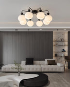Clérachic flush-mount light with black arms above a tufted white sofa, a dark slatted wall and a curved coffee table.