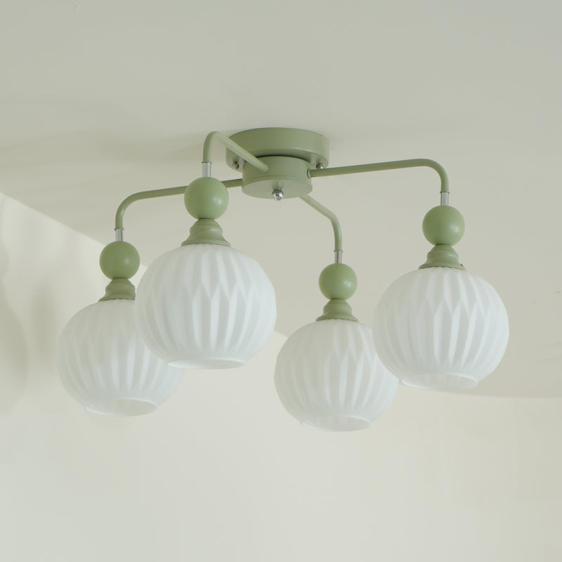 Close view of the green Clérachic ceiling light, with ribbed frosted globes hanging from arms that curve out of a round canopy.