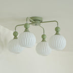 Close view of the green Clérachic ceiling light, with ribbed frosted globes hanging from arms that curve out of a round canopy.