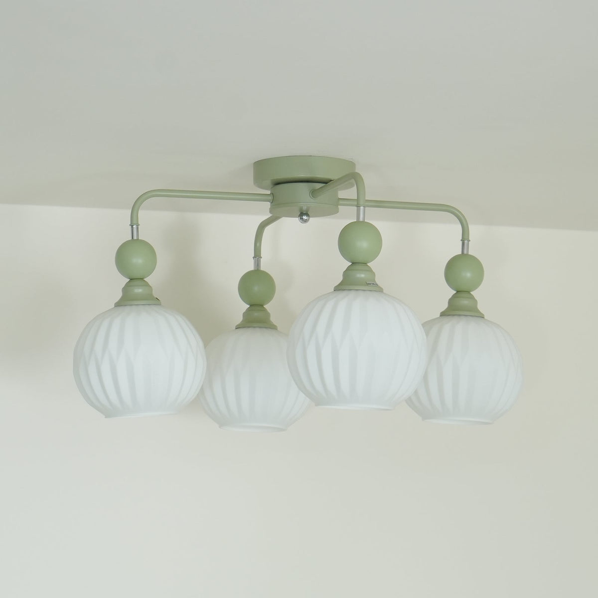 Side view of the four-globe Clérachic ceiling light, its green arms bending down from a round canopy to ribbed globes.