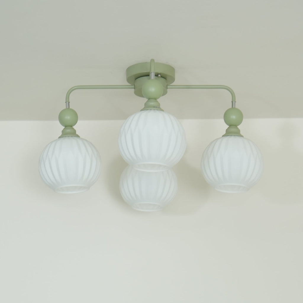 Low angle on a green Clérachic ceiling light with four unlit ribbed globes, two of them overlapping at the centre.