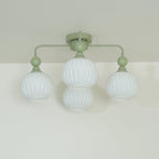 Low angle on a green Clérachic ceiling light with four unlit ribbed globes, two of them overlapping at the centre.