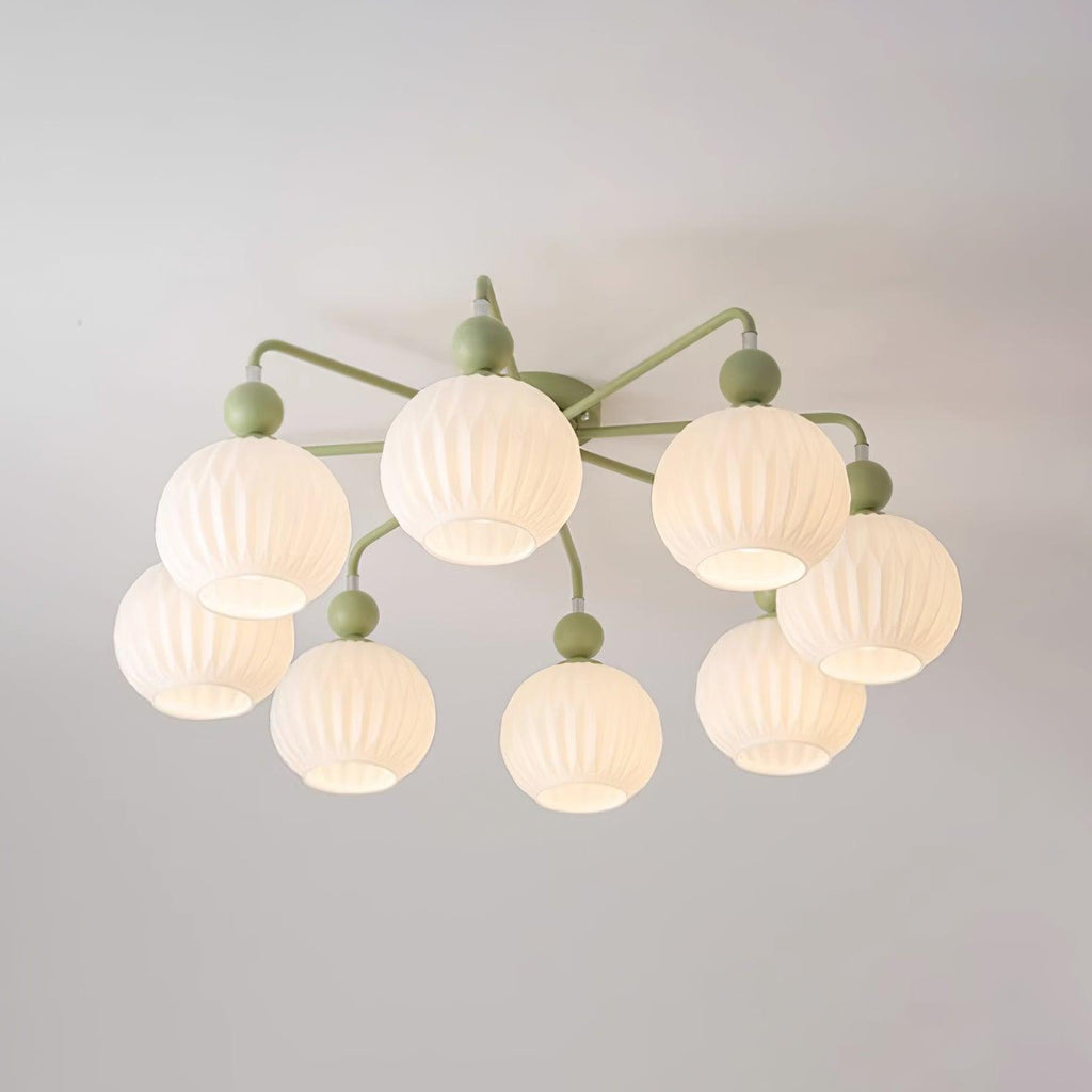 Lit eight-globe Clérachic ceiling light in green, the ribbed globes glowing warm on a pale ceiling.