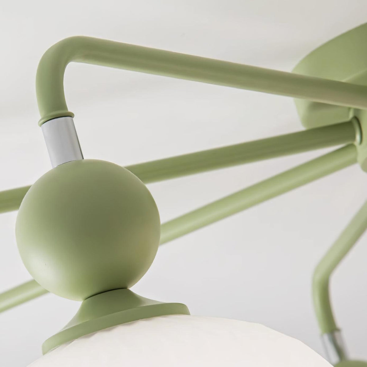Close view of a green ball joint, a silver collar and the thin arms of this Clérachic ceiling light.
