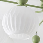 Close view of a ribbed frosted glass globe, its open rim and a green ball on the arm of this Clérachic ceiling light.