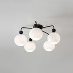 Five ribbed white globes on black curved arms, on a Clérachic ceiling light photographed from below.