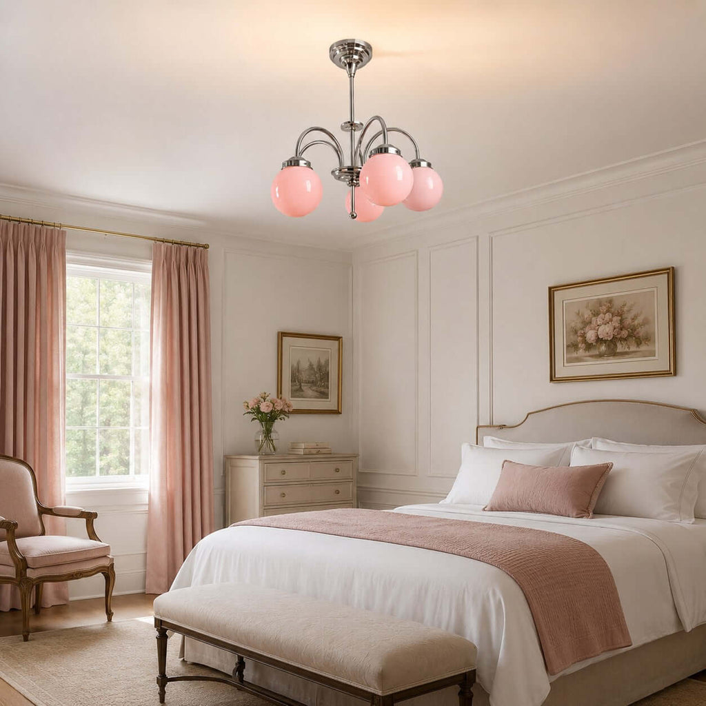 Pink globe glass Clérachic chandelier hanging in a pale bedroom with rose curtains and a white bed with a blush throw.