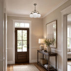 White globe Clérachic chandelier in a hallway, with a glazed wooden front door, a console table, a table lamp and a tall mirror.
