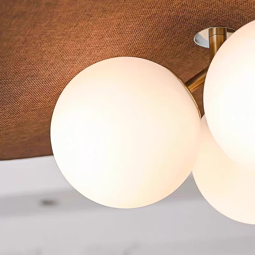 Close view of the textured brown fabric underside and a white opal glass globe on this Clérachic pendant, with its brass arm above.