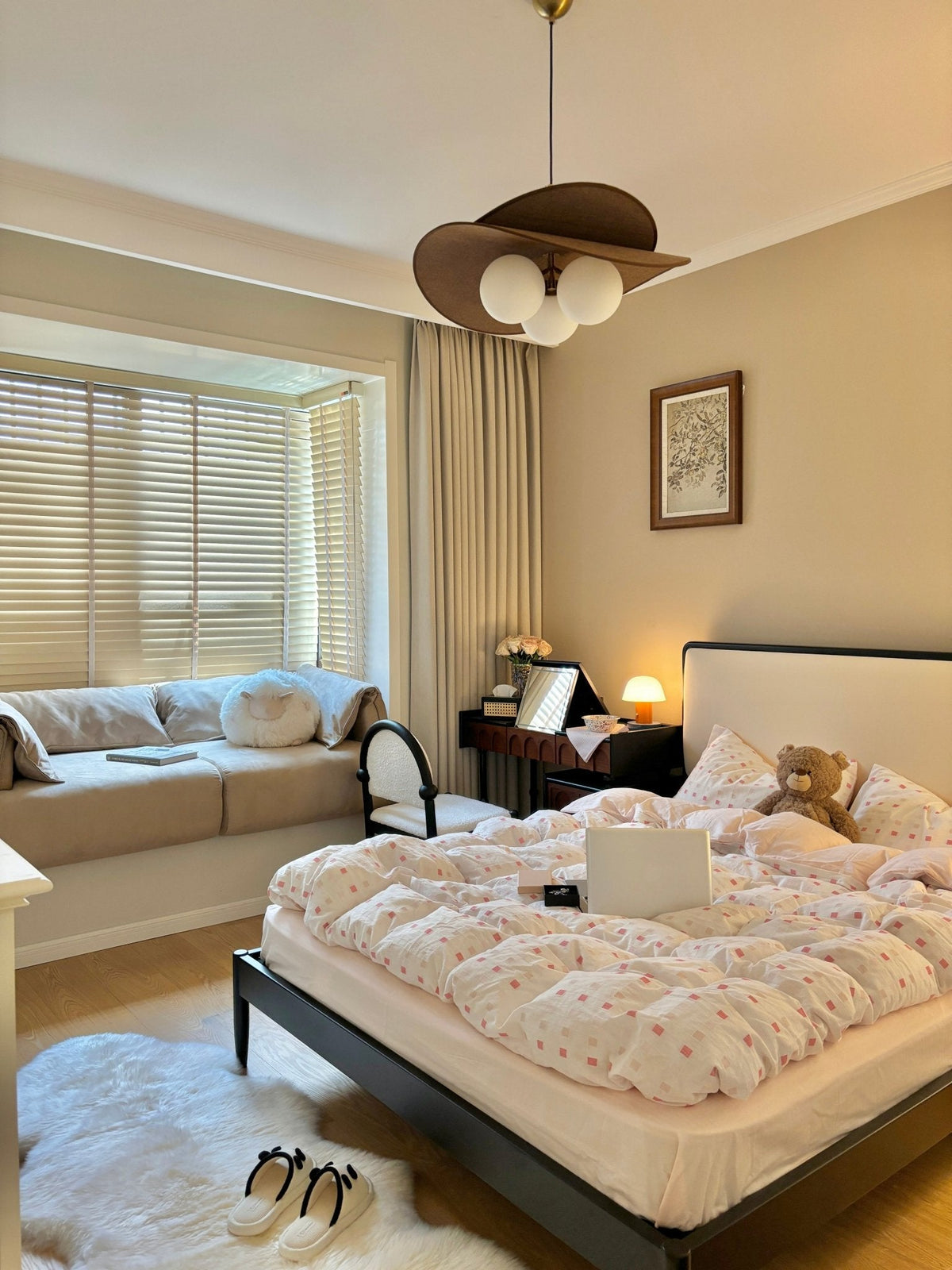 Clérachic pendant in a bedroom with a bay window and wooden blinds, above a quilted bed with white-framed headboard and a bench.