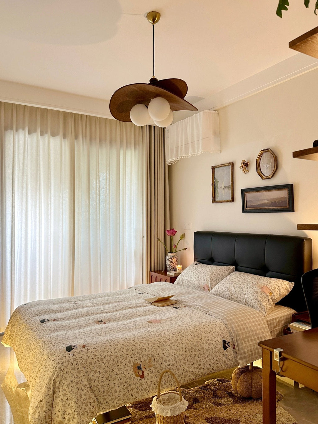 Another view of a Clérachic pendant beside sheer curtains, over a quilted bed with a black headboard and a basket at the foot.