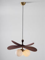 This Clérachic pendant hangs on a long black cord from a brass canopy against a pale grey backdrop, with its globes softly lit.
