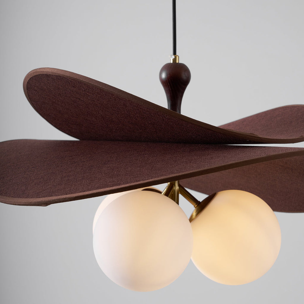Close view of three lit opal globes under the layered brown petals of this Clérachic pendant, with a walnut-toned stem above.
