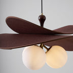 Close view of three lit opal globes under the layered brown petals of this Clérachic pendant, with a walnut-toned stem above.
