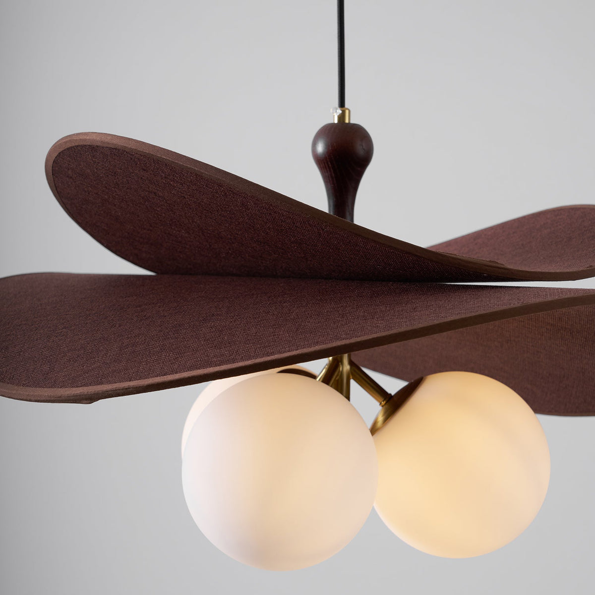Close view of three lit opal globes under the layered brown petals of this Clérachic pendant, with a walnut-toned stem above.