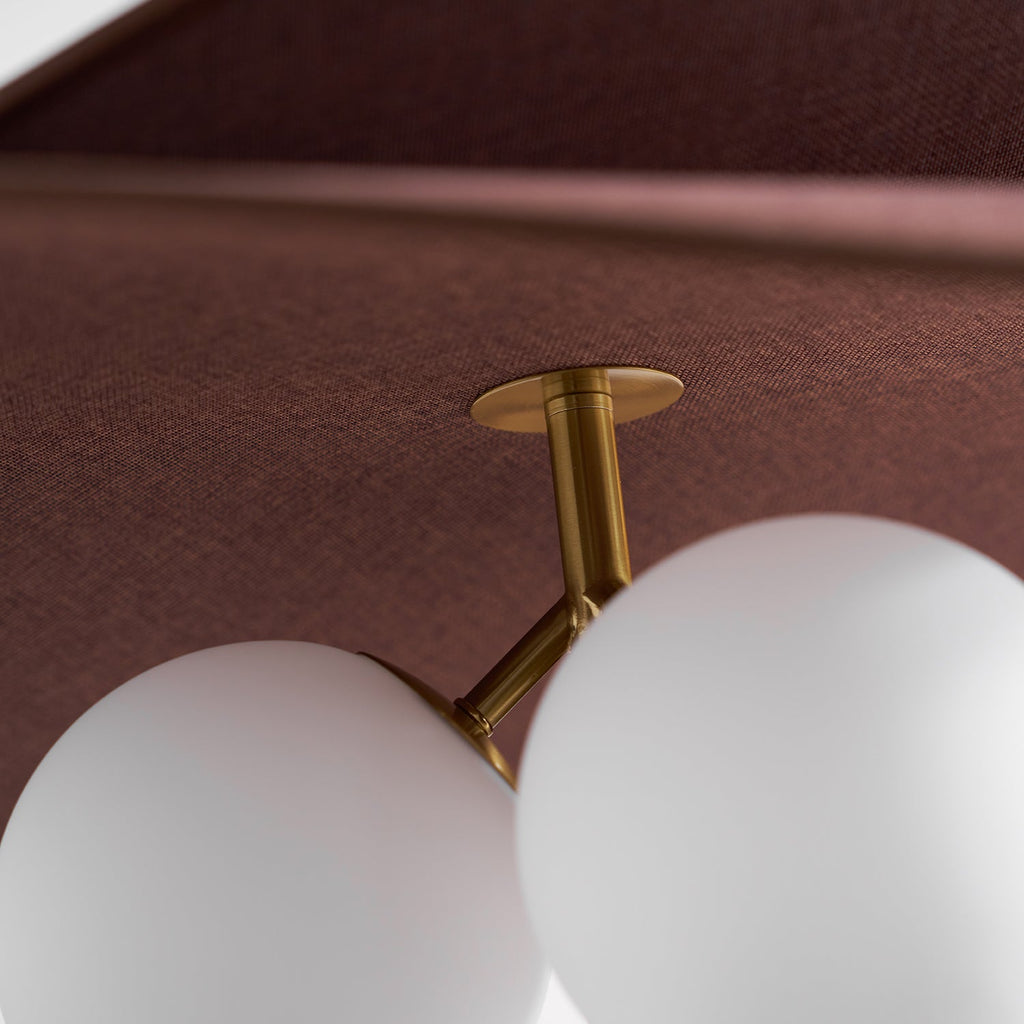 Close view of the brushed brass arm joining the white opal globes beneath the woven brown underside of this Clérachic pendant.