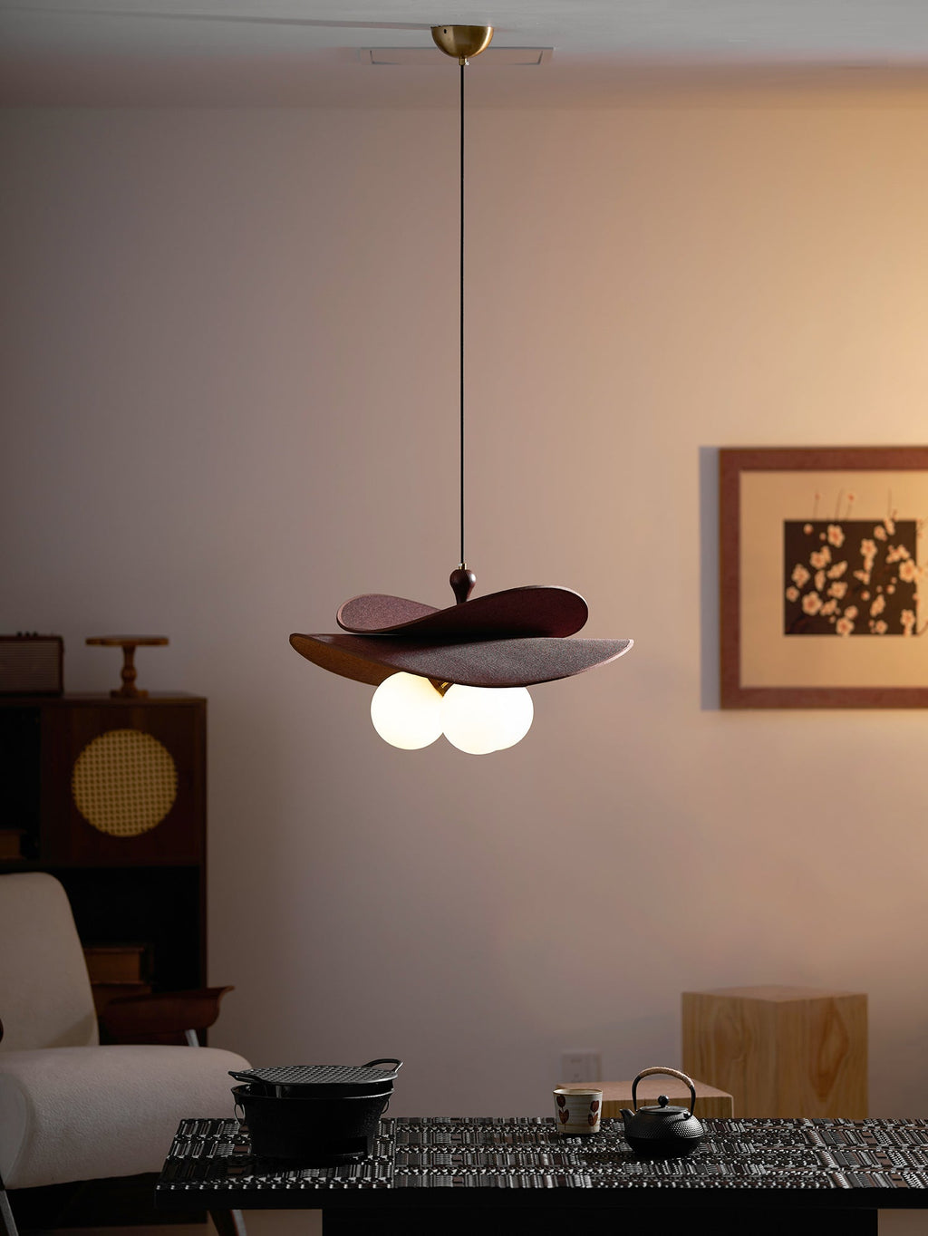 Dimly lit room with this Clérachic pendant glowing warm above a dark table, a cane-fronted cabinet and a framed print.