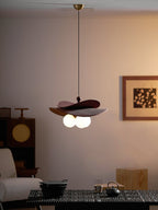 Dimly lit room with this Clérachic pendant glowing warm above a dark table, a cane-fronted cabinet and a framed print.
