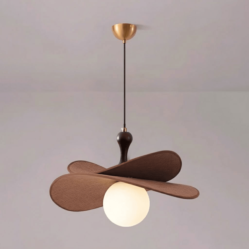 This Clérachic pendant on a brass canopy with a single lit globe visible under two brown petals, against a soft pink-grey wall.