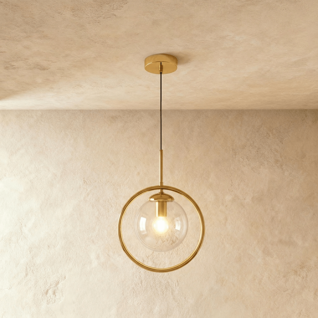 Clérachic gold ring pendant with a clear glass globe and a lit bulb on a slim rod and cord, shown in a studio