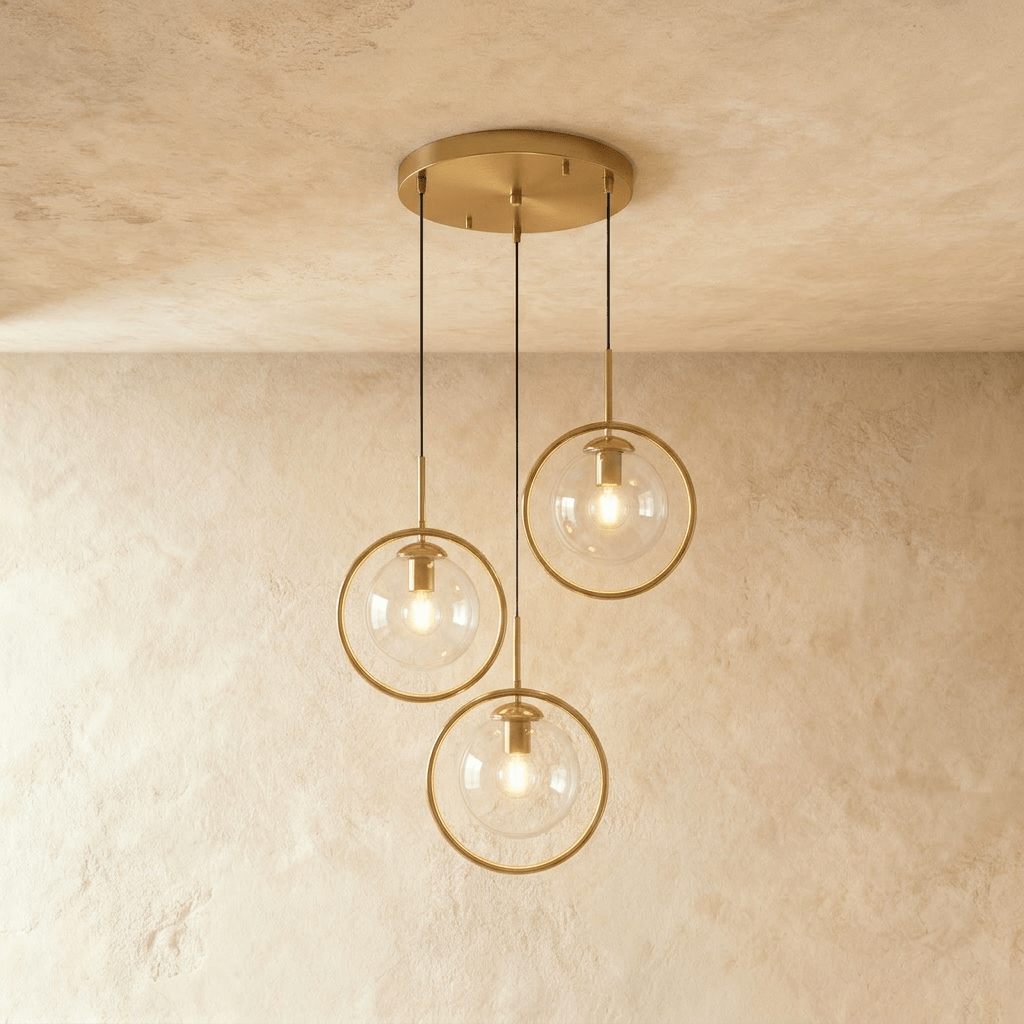 Clérachic cluster of three gold ring pendants with clear glass globes on a round gold canopy, in a studio