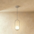 Clérachic silver oval ring pendant with a white opal glass globe at the bottom of the frame, hung in a studio