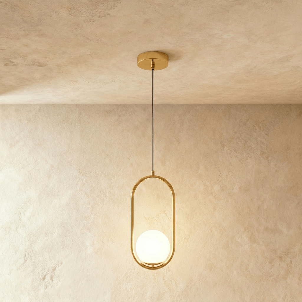 Clérachic gold oval ring pendant with a glowing white opal glass globe at the base of the frame, shown in a studio